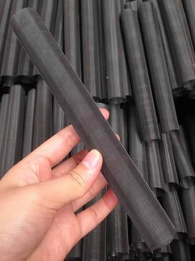 There is a black wire cloth extruder screen tube in one hand.