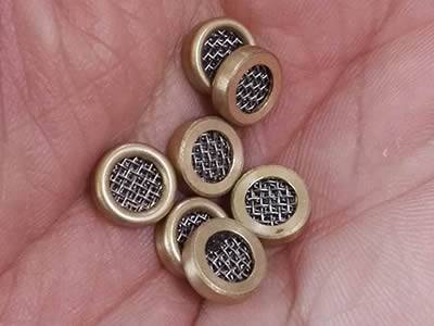 There are several small multilayer extruder discs with brass rims in one hand.