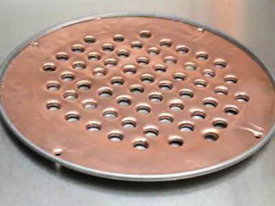 There is a copper perforated extruder disc with frame.