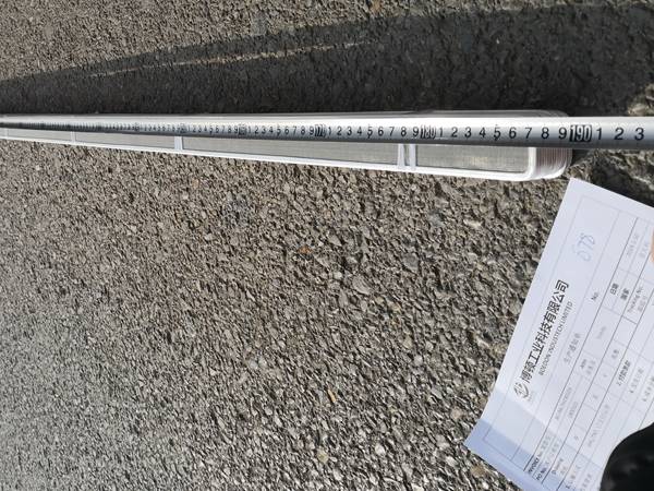 Two workers are measuring the length of meltblown spinneret filter mesh with meter ruler.