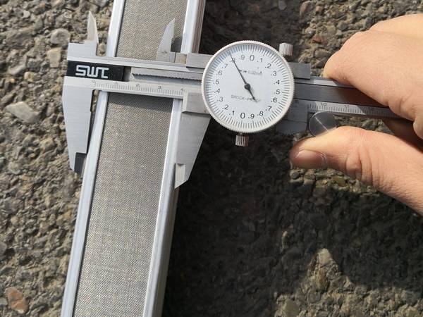 A worker is measuring the width of meltblown spinneret filter mesh with vernier caliper.
