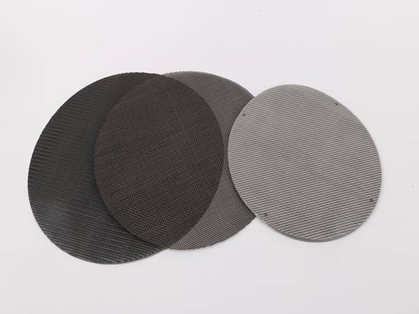 Three pieces of extruder screens on gray background.